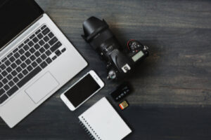 Aerial view of a laptop, camera, smartphone, memory card, recorder and notebook on a table