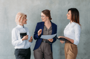 Three white women in a standing meeting